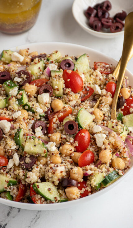 A white bowl filled with greek quinoa chickpea salad.
