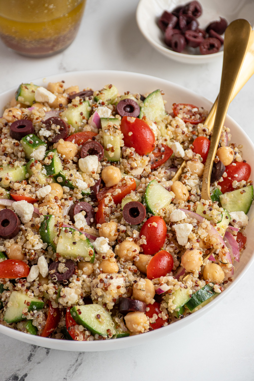 A white bowl filled with greek quinoa chickpea salad.