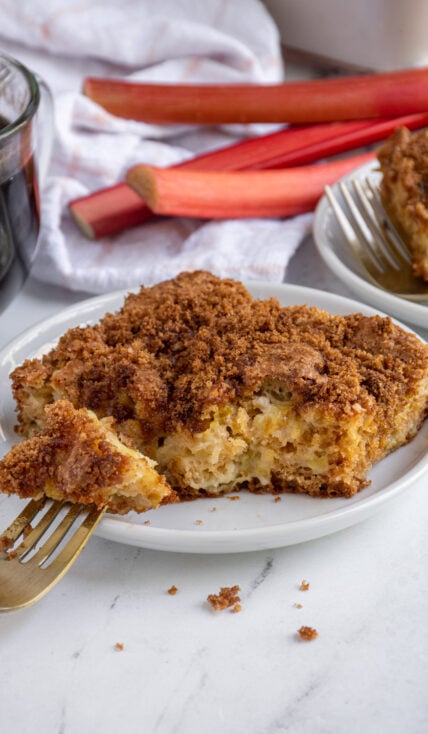 A plate with a slice of rhubarb coffee cake with a bite on a fork.