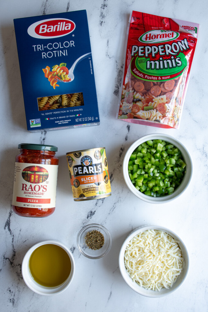Ingredients needed to make pizza pasta salad on a table.