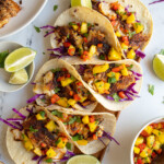 Pinterest pin with logo over lay "the Schmidty Wife", image of blackened fish tacos with mango salsa on a tray.