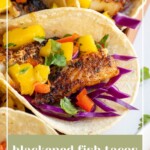 Pinterest pin with text over lay "Blackened Fish Tacos with Mango Salsa", image of blackened fish tacos with mango salsa on a tray.