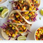Pinterest pin with text over lay "Blackened Fish Tacos with Mango Salsa", image of blackened fish tacos with mango salsa on a tray.