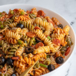 Pinterest pin with text overlay "Pizza Pasta Salad" with image of a bowl filled with colorful pizza pasta salad.