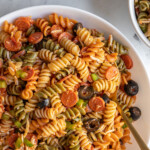 Pinterest pin with text overlay "Pizza Pasta Salad" with image of a bowl filled with colorful pizza pasta salad.