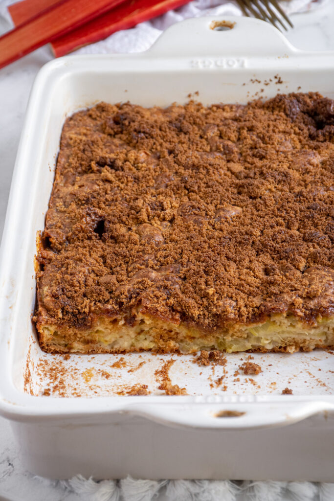 A baking dish with rhubarb coffee cake with a slice taken out.