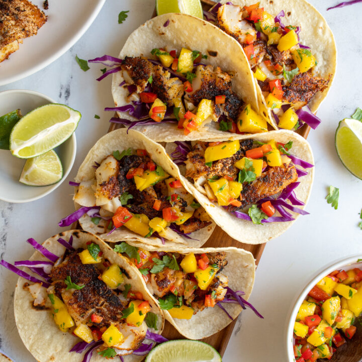 A large platter with six blackened fish tacos with mango salsa and red cabbage.