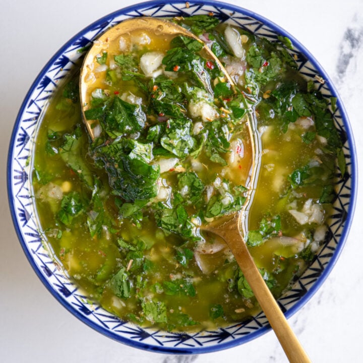 Bowl of green chimichurri sauce with a gold spoon.