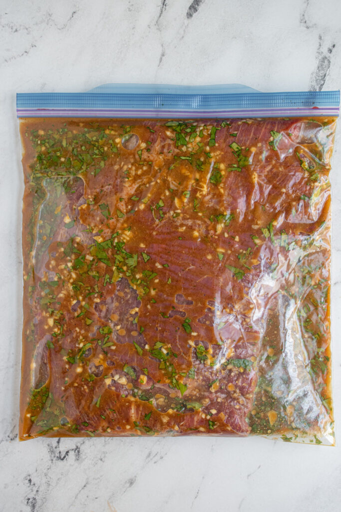 A ziplock bag with a flank steak and carne asada marinade in it.