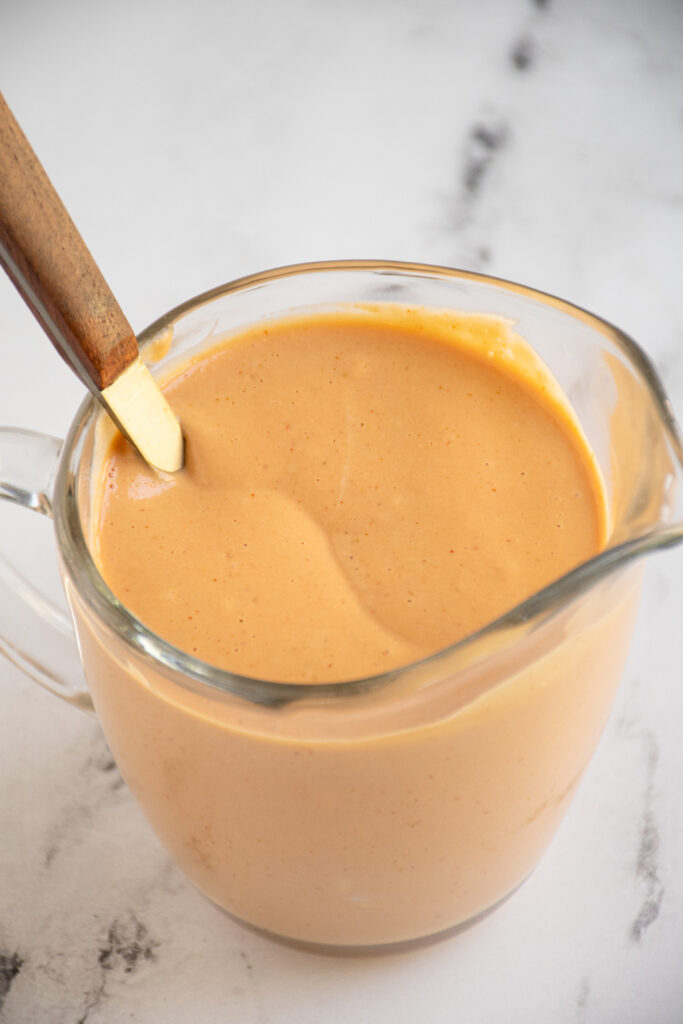 A cup full of homemade Big Mac sauce with a spoon.