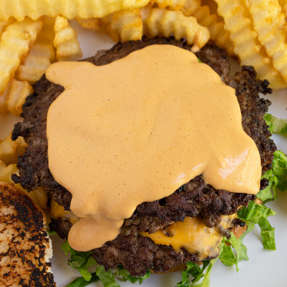 Homemade Big Mac sauce spread across the top of a burger.