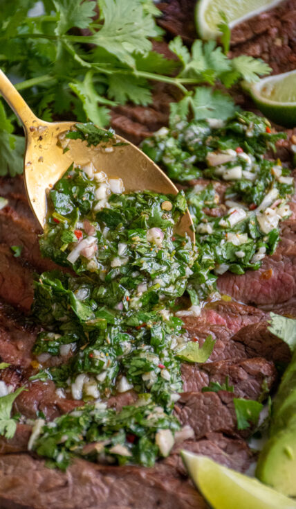 Bright green Chimichurri sauce being spooned onto grilled meat.