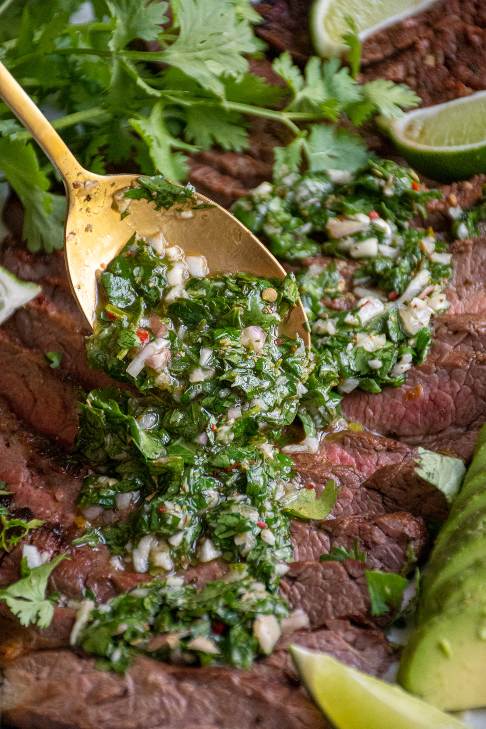 Bright green Chimichurri sauce being spooned onto grilled meat.