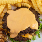 Pinterest pin with text overlay "Homemade Big Mac Sauce", image of a burger patty with Big Mac sauce spread over the top of it.
