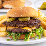 Pinterest pin with text overlay "Blackstone Smash Burgers" with the image of a double smash burger in a bun with lettuce and pickles.