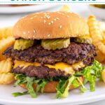 Pinterest pin with text overlay "Blackstone Smash Burgers" with the image of a double smash burger in a bun with lettuce and pickles.