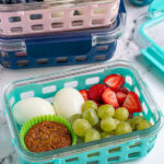 Pinterest pin with the image of a breakfast bistro boxes with eggs, muffin, and fruit.