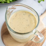 Pinterest pin with text overlay "Hummus Salad Dressing", image of a serving glass filled with creamy hummus salad dressing.