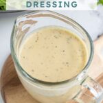 Pinterest pin with text overlay "Hummus Salad Dressing", image of a serving glass filled with creamy hummus salad dressing.