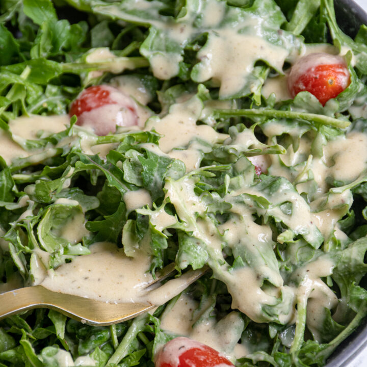 Close up of hummus salad dressing on top of fresh greens.