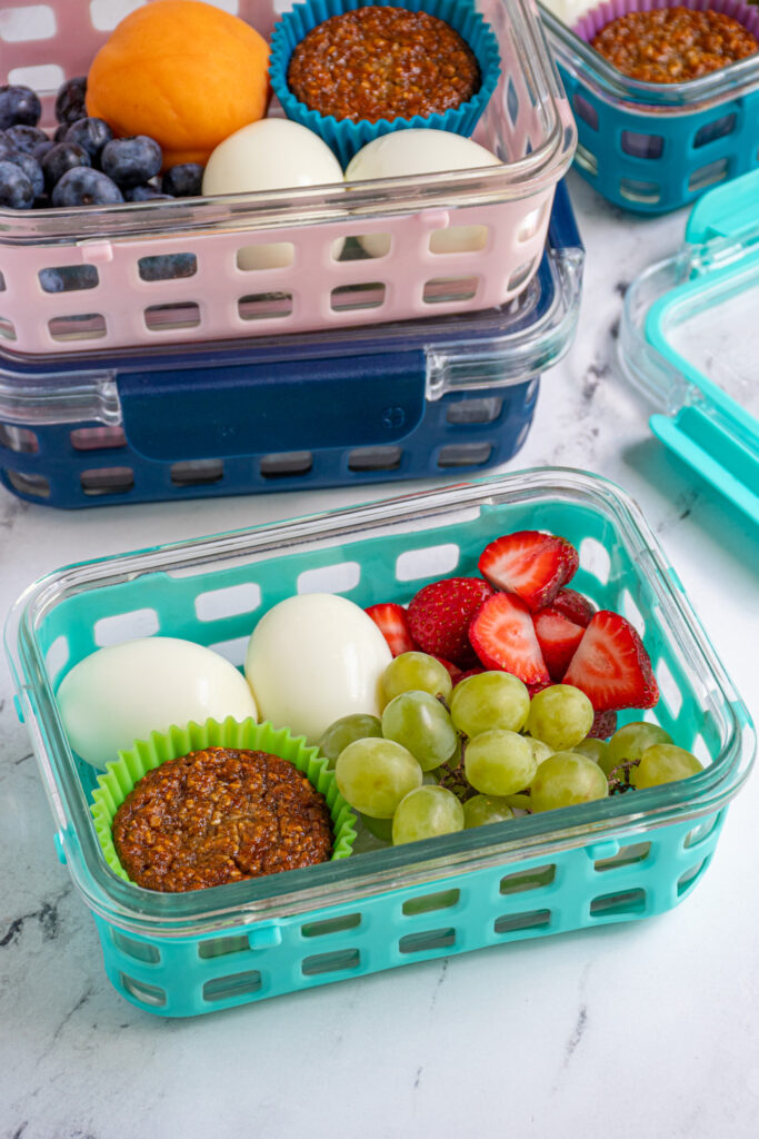 A breakfast bistro box with hard boiled eggs, fruits, and a muffin.