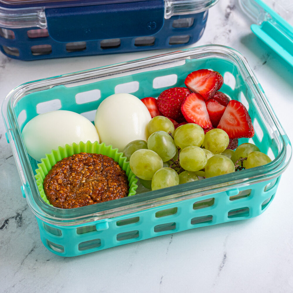 A breakfast bistro box with hard boiled eggs, fruits, and a muffin.