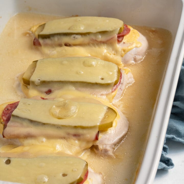 Four chicken breast cutlets with cuban sandwich toppings baked and ready to eat.