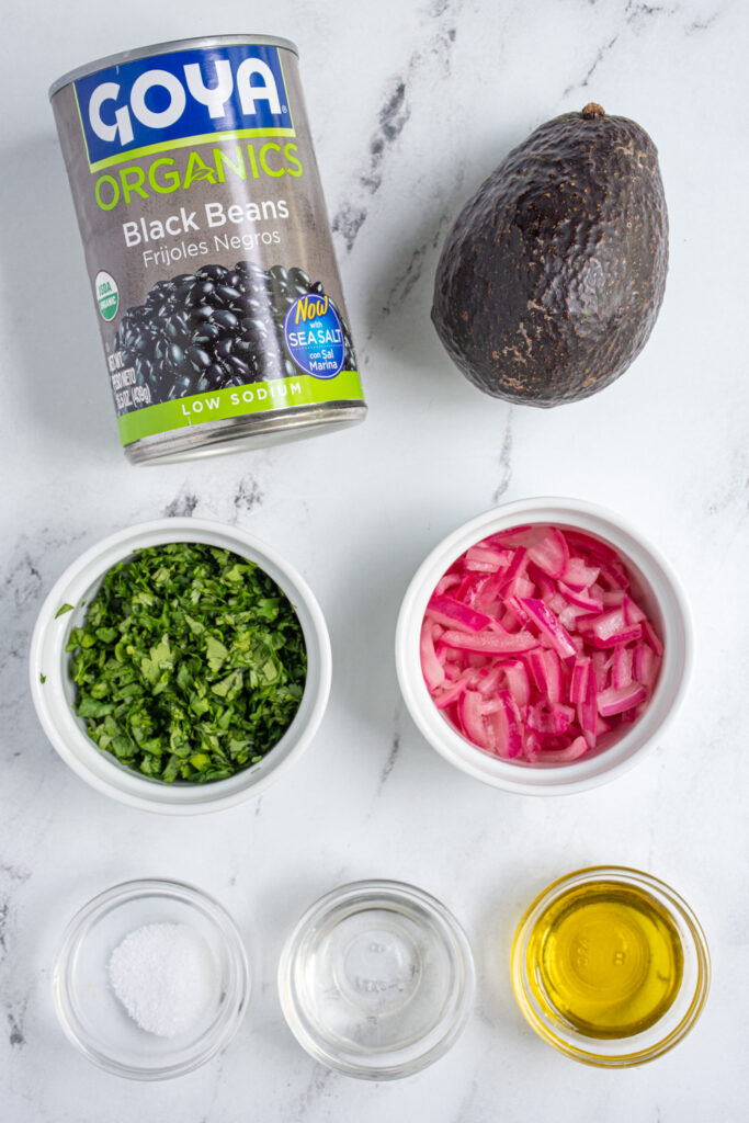 Ingredients needed to make avocado black bean salsa laid out on a tabletop.