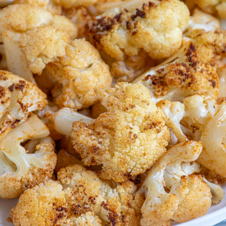 Close up of a piece of crispy air fryer cauliflower in a white bowl.