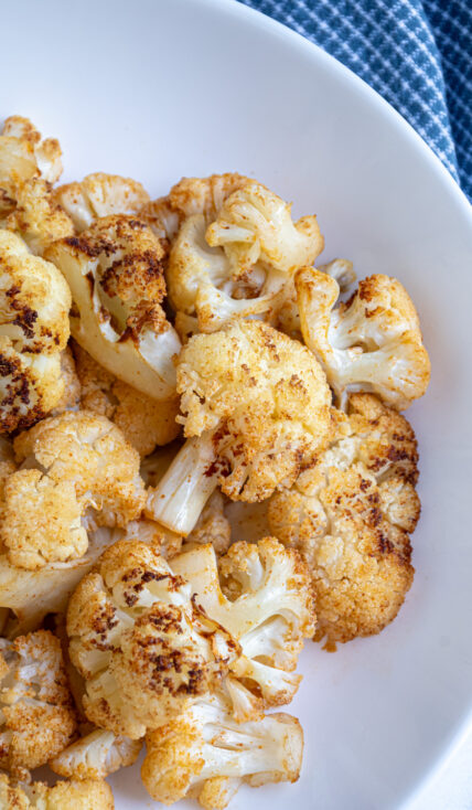 Freshly made air fryer cauliflower in a white bowl showing off the seasoned and crispy cauliflower.