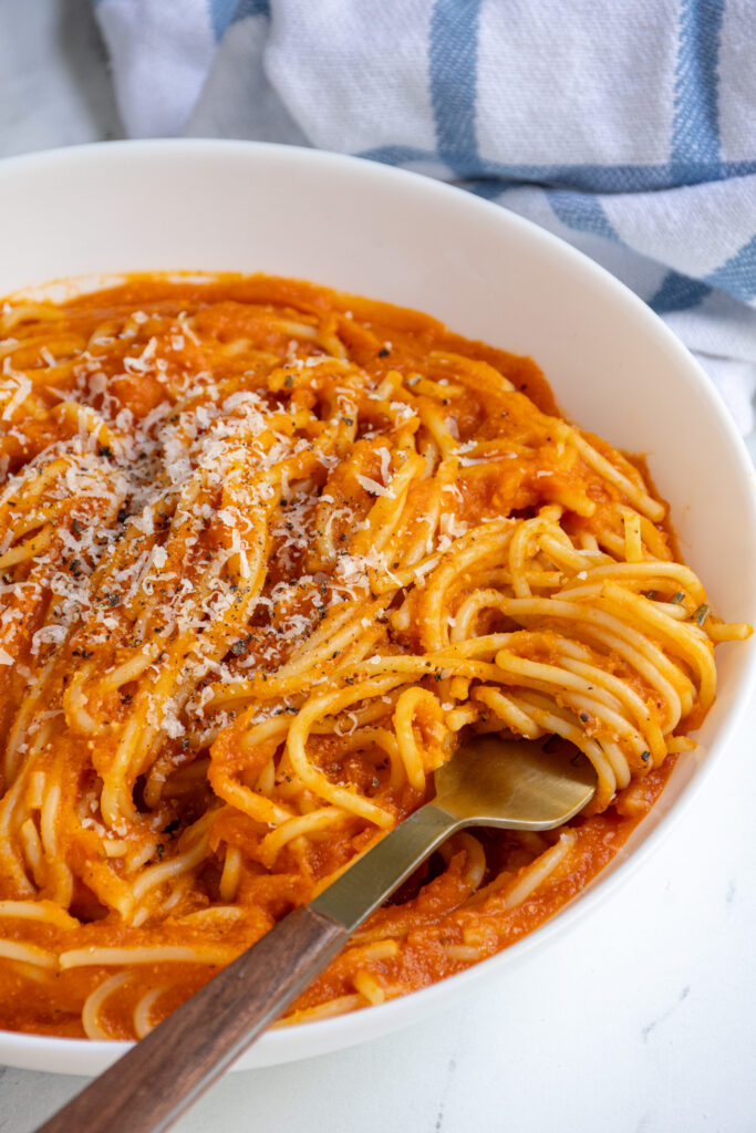 A fork swirled around pasta in a bowl filled with spaghetti served with homemade butternut squash pasta sauce.
