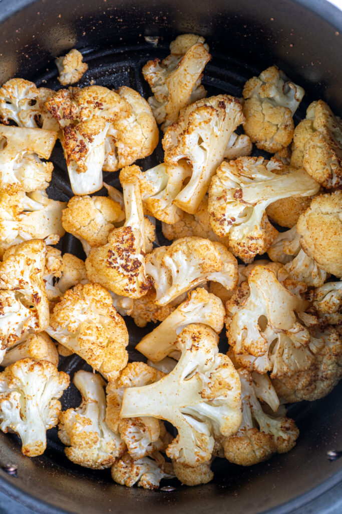 Close up of crispy cauliflower in an air fryer basket.