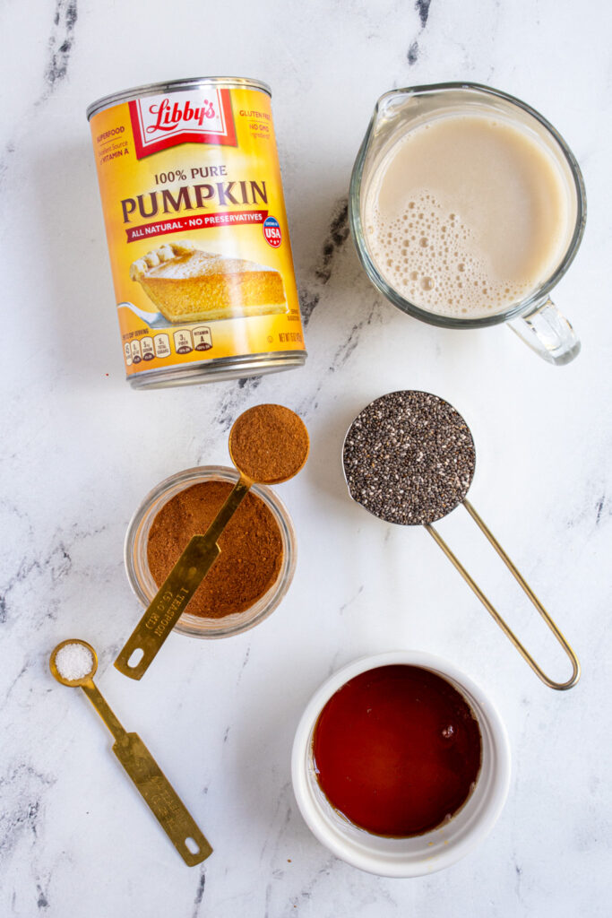Ingredients needed to make pumpkin chia seed pudding laid out on a table top.