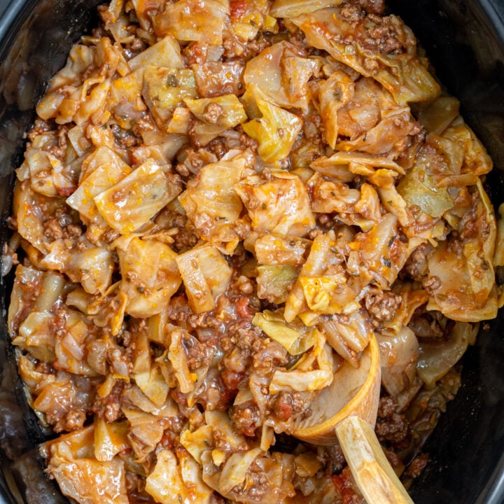 Overhead view of a black crockpot with unstuffed cabbage rolls inside.
