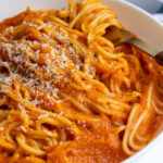 Pinterest pin with text overlay "Butternut Squash Pasta Sauce", image of a white bowl filled with spaghetti covered in homemade butternut squash pasta sauce.