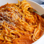 Pinterest pin with text overlay "Butternut Squash Pasta Sauce", image of a white bowl filled with spaghetti covered in homemade butternut squash pasta sauce.
