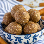 Pinterest pin with text overlay "Chai Spiced Energy Ball", image of a blue and white bowl overfilled with chai spiced energy bites.
