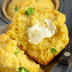Pinterest pin with text overlay "Jalapeño Cornbread Muffins", image of a cornbread muffin cut in half with a smear of butter revealing a tender inside.