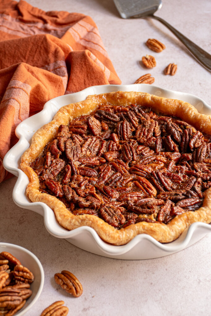A white pie plate with a bourbon pecan pie.