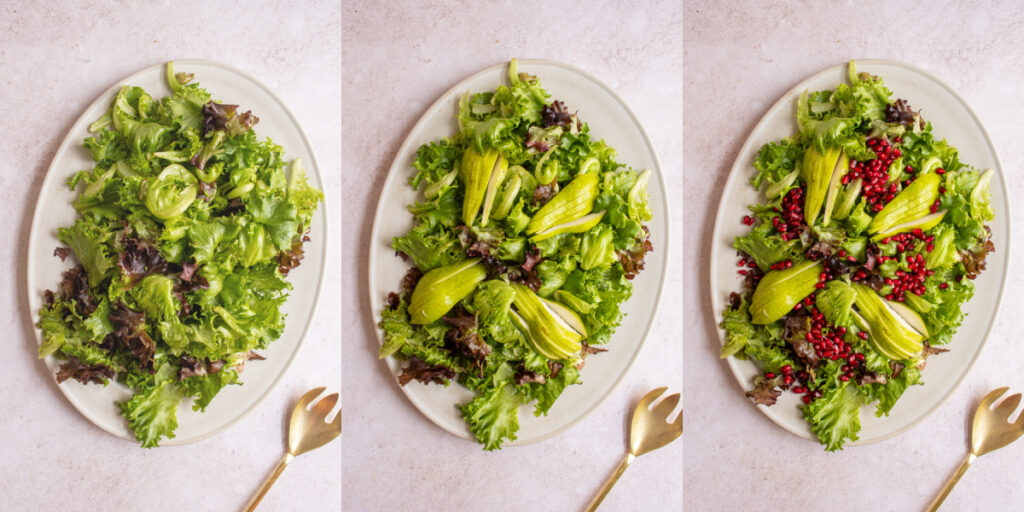 Building a winter salad on a platter with mixed greens, pears, and pomegranate seeds being added.