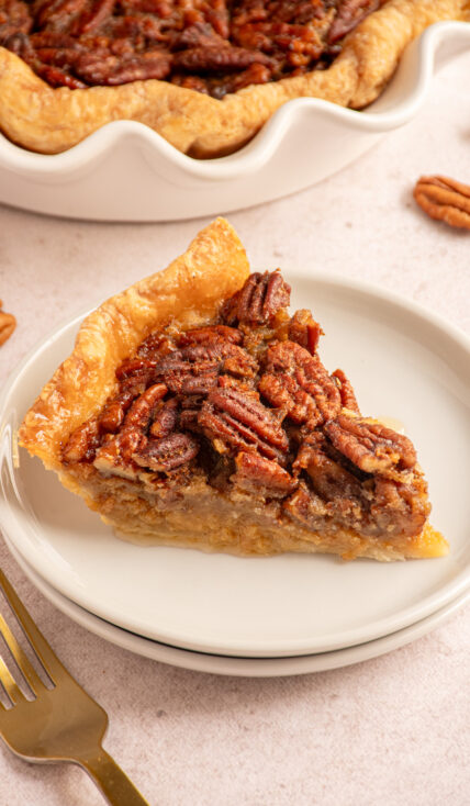 A slice of bourbon pecan pie on a small white plate.