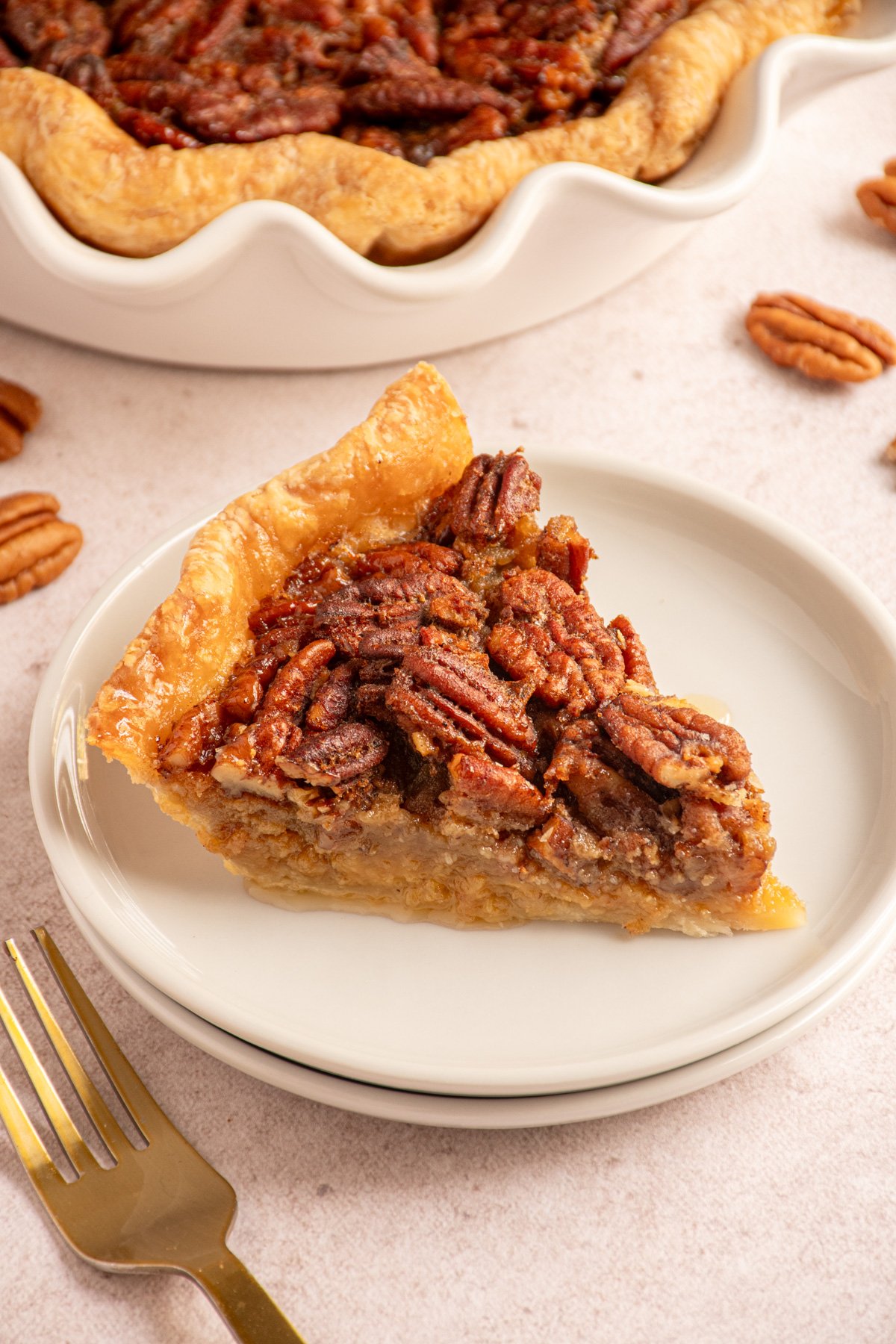 A slice of bourbon pecan pie on a small white plate.