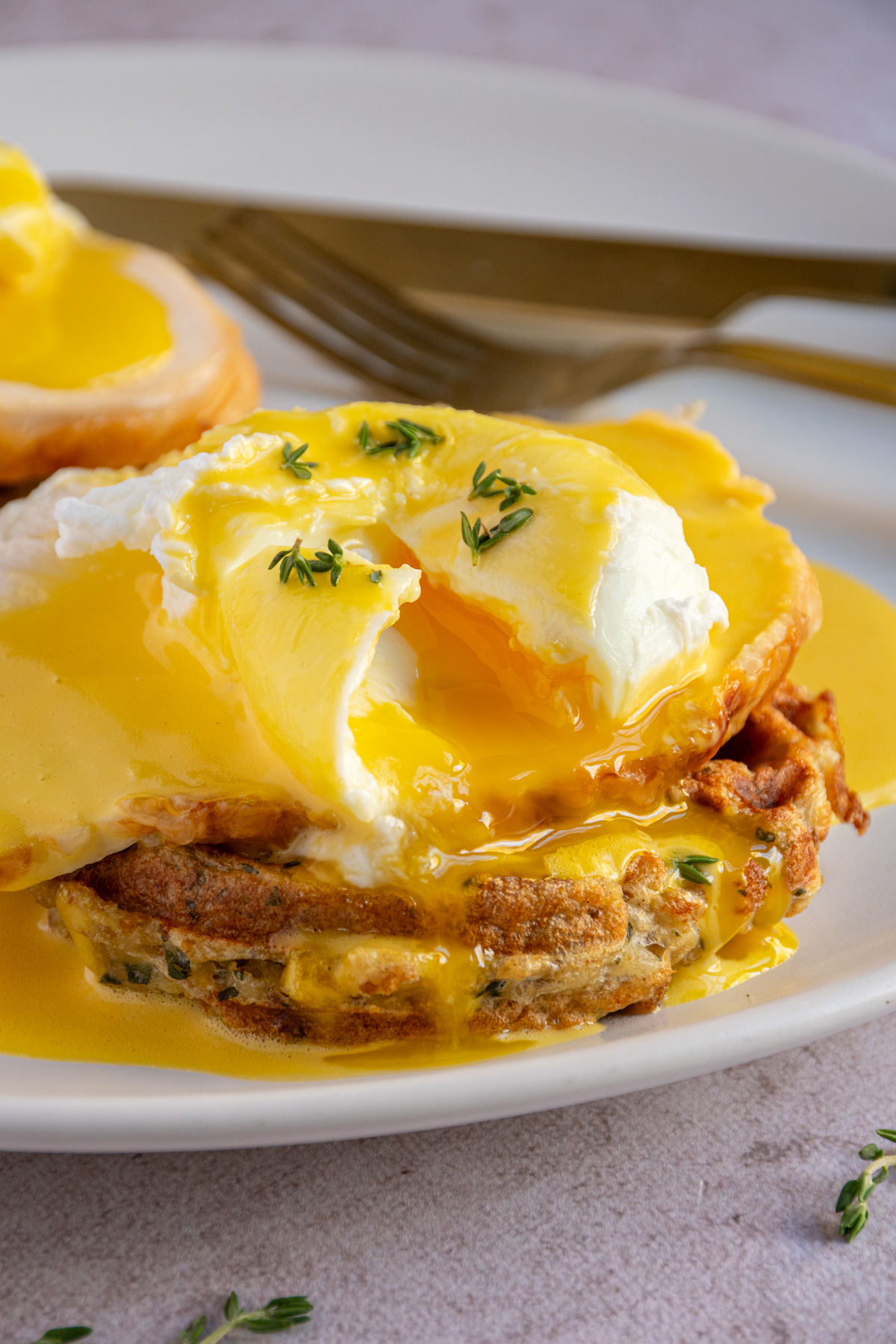 An opened poached egg with runny yolk on top of a thanksgiving eggs benedict with a stuffing waffle and turkey.
