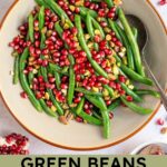 Pinterest pin with text overlay "Green Beans with Pomegranate & Pistachios", image of a bowl of bright green beans with red pomegranate seeds and pistachios.