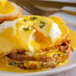 Pinterest pin with text overlay "Leftover Thanksgiving Eggs Benedict", image of a poached egg opened with runny yolk with hollandaise sauce, turkey, and a stuffing waffle.