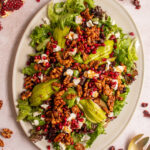 Pinterest pin with text overlay 'Winter Salad with Candied Walnuts', image of a large platter covered in a colorful and festive salad.