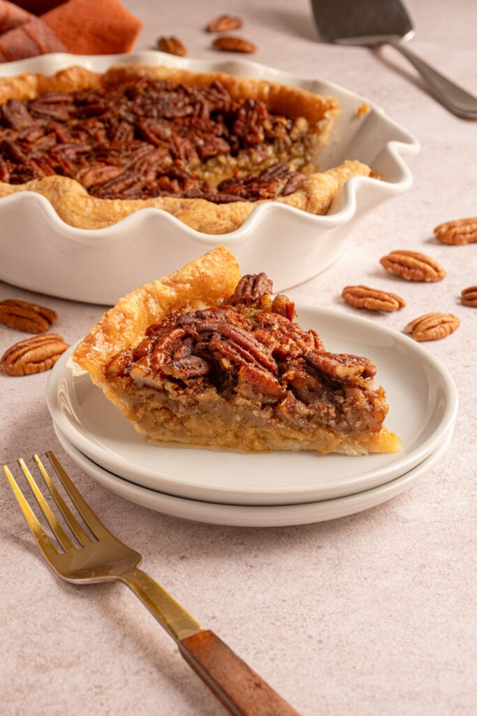 A slice of bourbon brown butter pecan pie on a small white plate.