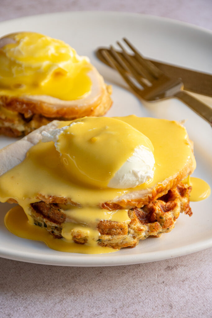 A thanksgiving eggs benedict with a stuffing waffle, turkey, a poached egg, and hollandaise sauce.