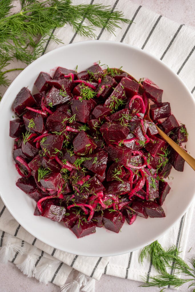 Overhead view of a white bowl with simple beet salad topped with fresh dill.