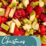 Pinterest pin with test overlay 'Christmas Fruit Salad", image of a white serving bowl filled with red and green fruits.